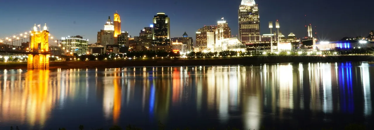 The Roebling Suspension Bridge lit at dusk with the Cincinnati skyline across the Ohio River