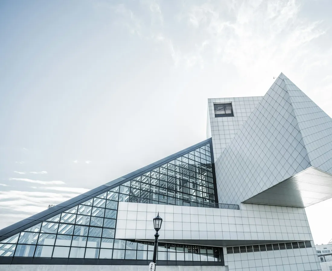 White geometric building with a glass atrium under a bright sky